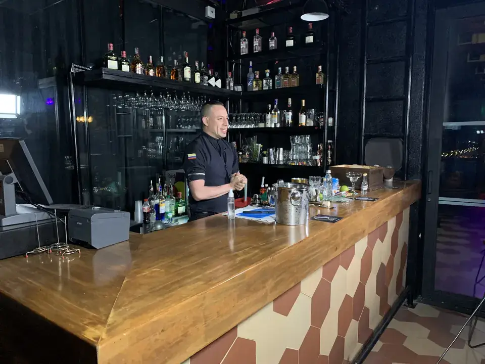 A presenter behind a wooden bar during a location filming session